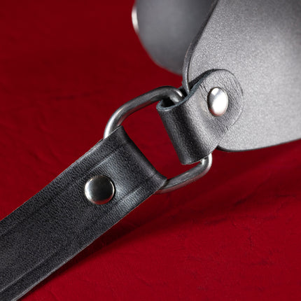 Close-up of nickel D-ring and riveted black leather strap on ball gag